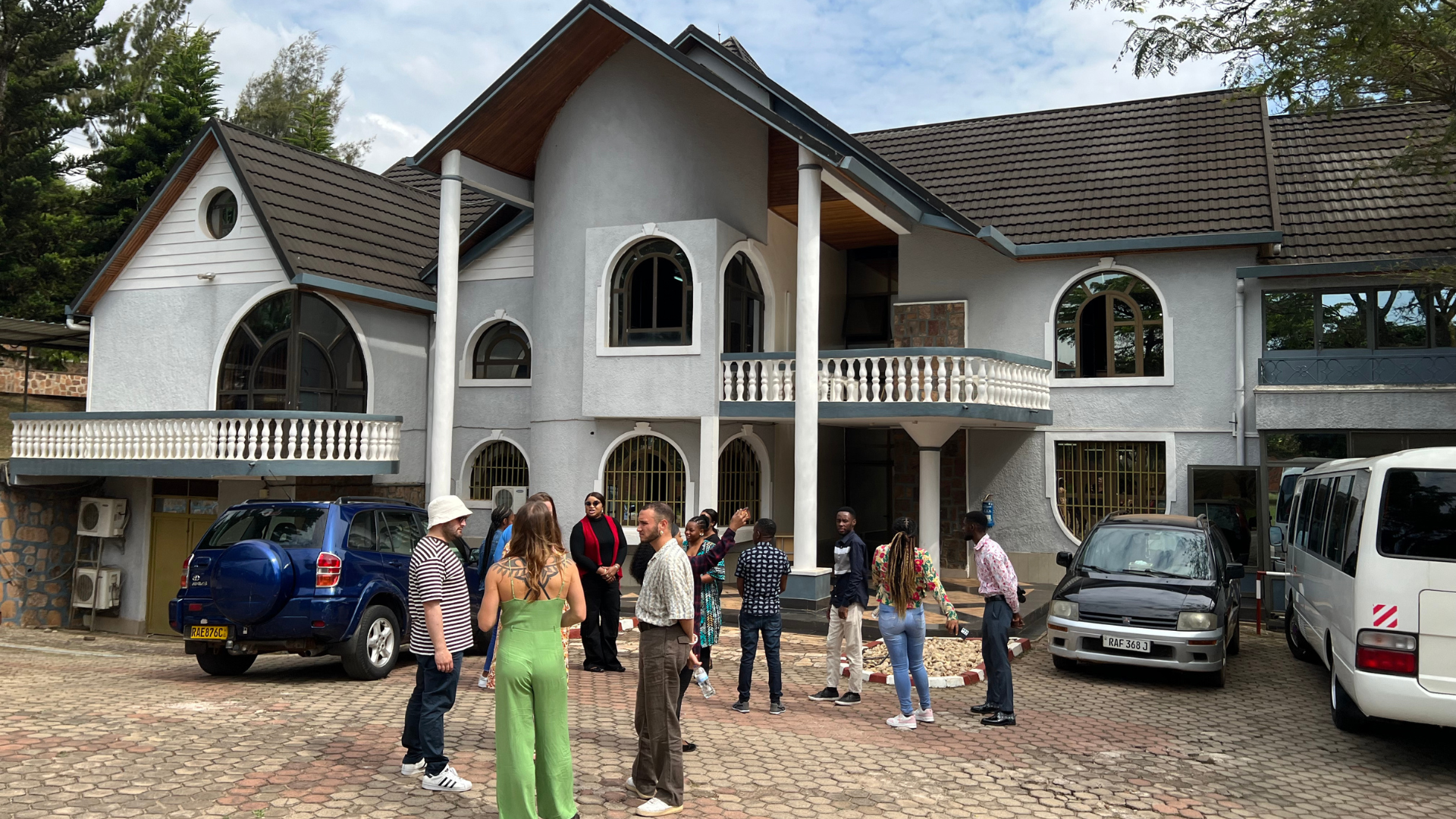 Two-story building shaped like a house and participants standing outsidew it looking at it