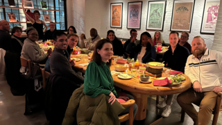 A Group photo around a table of both faculty and participants at dinner